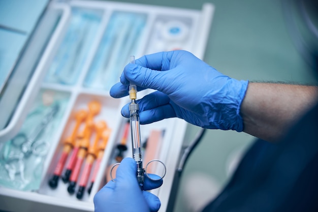 Male dentist taking painkiller injection for treatment