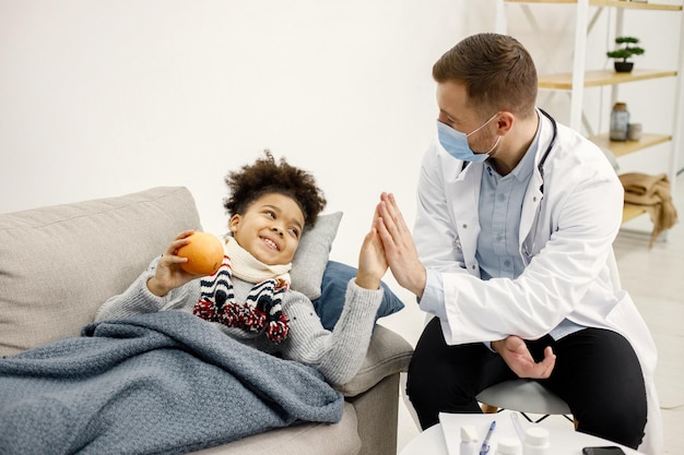 Male pediatrician give a five to sick little black girl