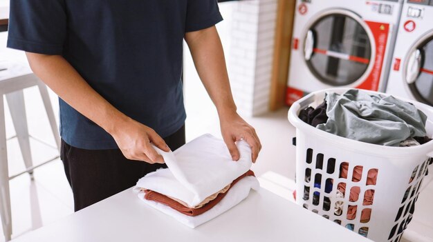 Man doing launder holding basket with dirty laundry of the washing machine in the public store laundry clothes concept