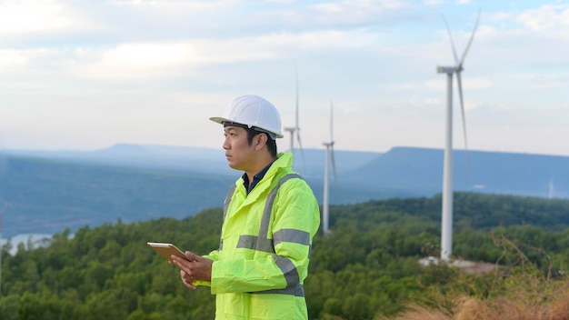 Photo a man engineer is wearing a protective helmet on her head using tablet analytics