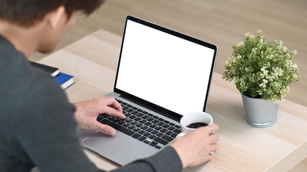 Man freelancer checking email on laptop computer and drinking coffee in the morning at home.