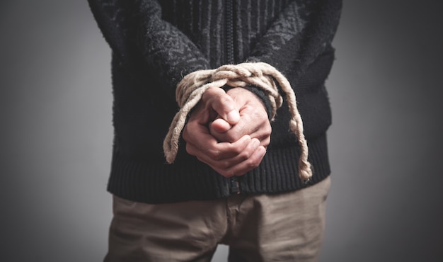 Photo man hands tied by a rope. imprisonment