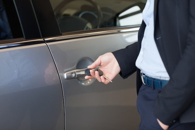 Man opening a car door with a key