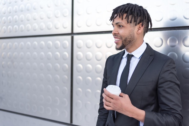 Man in suit drinking coffee at silver wall