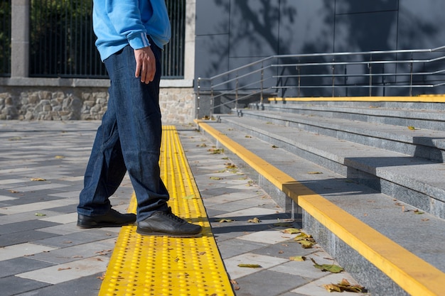 Man walking on yellow blocks of tactile paving for blind handicap.Braille blocks, tactile tiles for the visually impaired, Tenji blocks