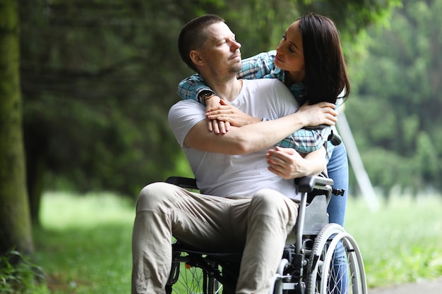 Man with paralyzed leg sit in wheelchair and look at his sister