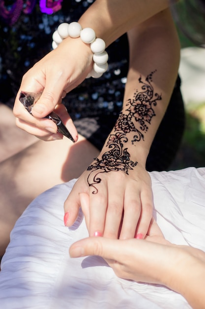 Photo master mehndi draws henna on a female hand