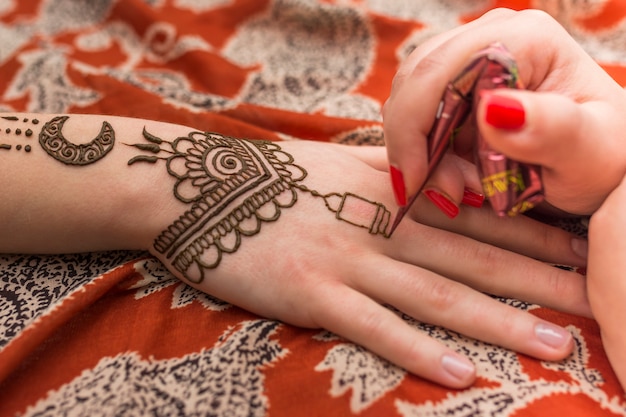 Photo master tattooing mehndi paint on woman hand