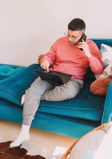 Medewerker aan het werk vanaf de bank thuis met zijn laptop vanwege de pandemie van het coronavirus