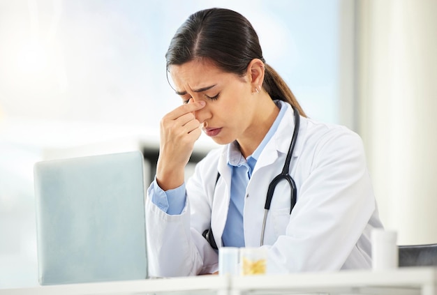 Foto medico donna di salute mentale triste e con il computer portatile alla sua scrivania in un ufficio moderno con un riflesso lente