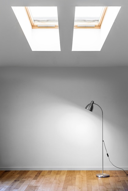 Metal floor lamp in empty room with shadow on white wall, and two dormer, copy space for text