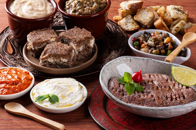 Meze is an oriental set of appetizers served in small bowls with babaganoush, curd, hummus, muhammara and kibbeh