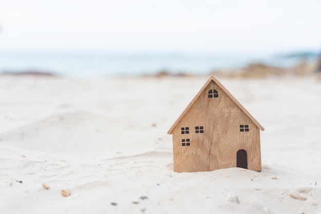 Miniature wooden house model on sand background concept for travel vacation real estate investment