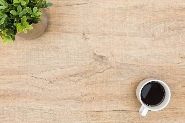 Minimal wood table with coffee and a small plant. 