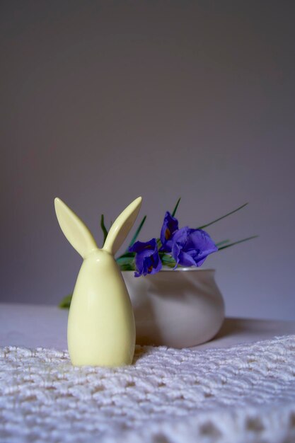 Photo minimalist irises on white ceramic vase on table with easter bunny