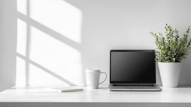 Photo a modern minimalist workspace featuring a laptop coffee cup and plant on a white desk