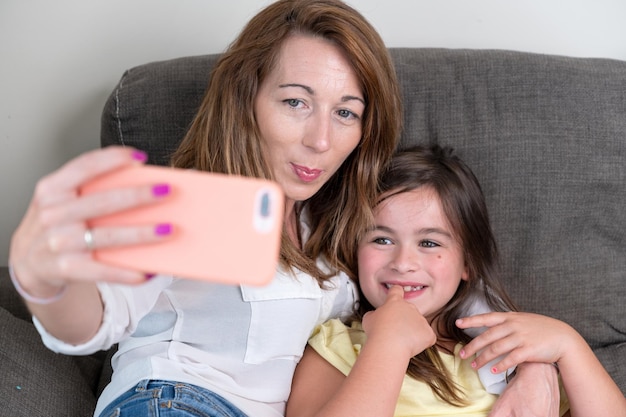 Mother and daughter taking selfie at home