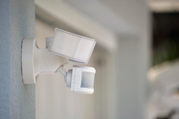 Motion sensor with light detector mounted on exterior wall of private house as part of security system