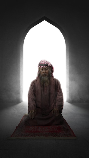 Muslim man with a beard wearing keffiyeh with agal in praying position salat on the prayer rug