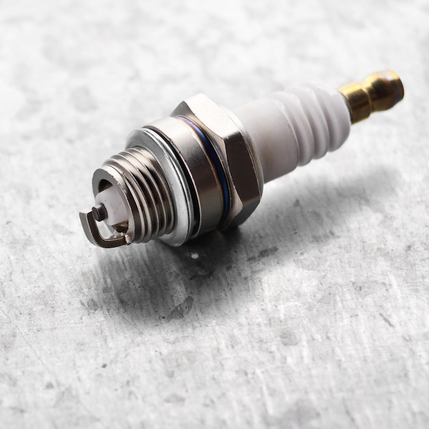 New spark plug for internal combustion engine on metal background. Space for text