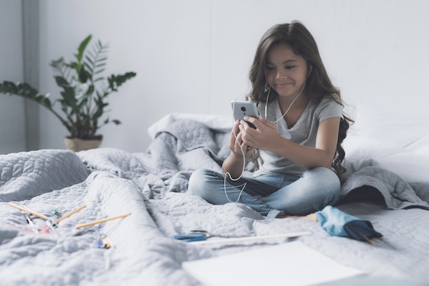 Nice Girl Listens Music in Headphones in Bedroom