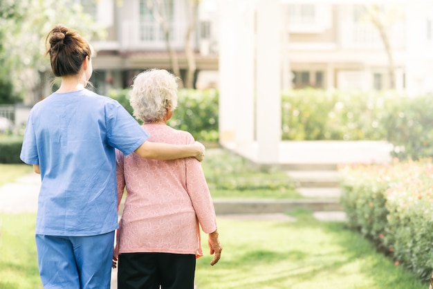 Photo nurse caregiver support walking with elderly woman outdoor