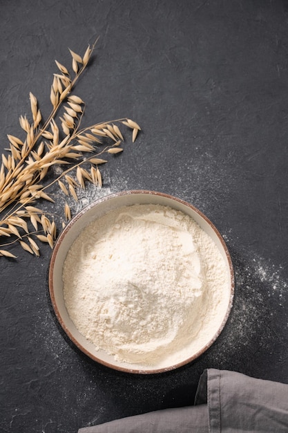 Foto farina d'avena sparsa su uno sfondo scuro con un tovagliolo ingredienti di cottura biologici concetto di cibo casalingo e sano