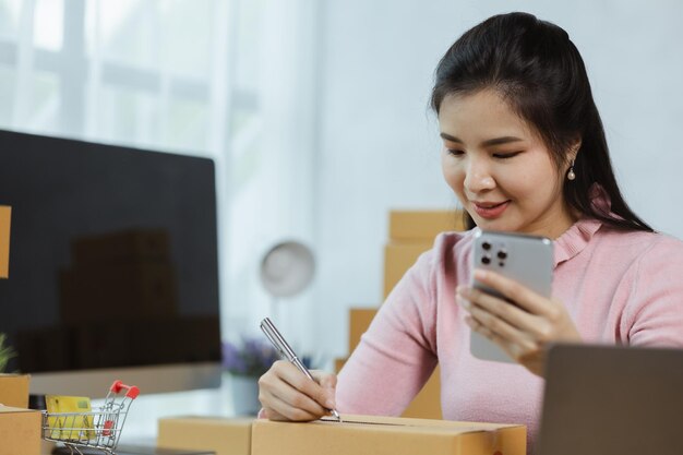 Photo online store salesperson is writing a customer's shipping address on parcel box before sending it to private carrier for delivery to customer the idea of opening an online store and packing products