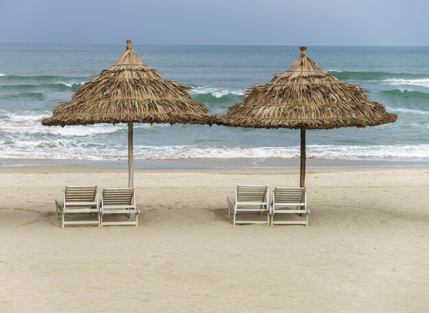 Photo palm shelter and sunbeds at the china beach in da nang, in vietnam. it is also called non nuoc beach. south china sea on the background.