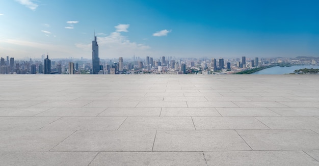 Panoramic skyline and empty square floor tiles with modern buildings