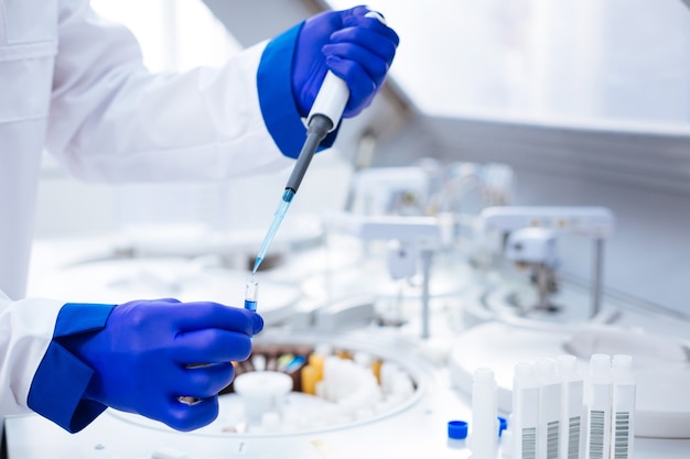 Parental test. Hands in blue gloves holding pipette and test tube with poured blue chemical