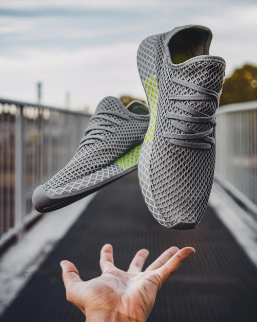 Photo a persons hand reaching up to a pair of sneakers that says  adidas