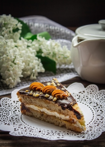 Piece of cake teapot and lilac on a brown wooden background