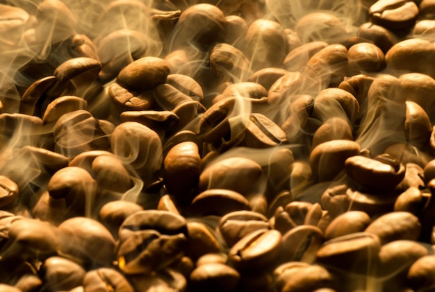 Foto un mucchio di chicchi di caffè tostati da cui esce fumo.