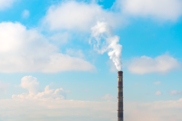 Photo pipe with smoke emissions during sunny weather with clouds.