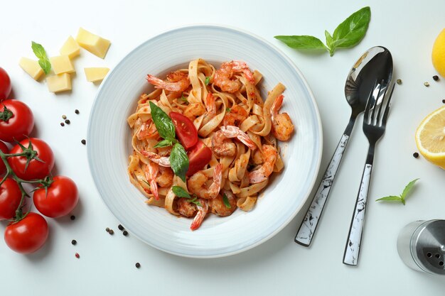 Plate of shrimp pasta and ingredients on white