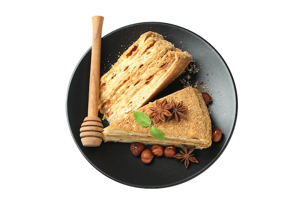 Plate with pieces of honey cake isolated on white background