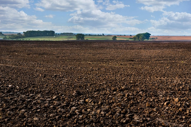 Photo plowed land in the foreground, groves and hills in the background of rural lands