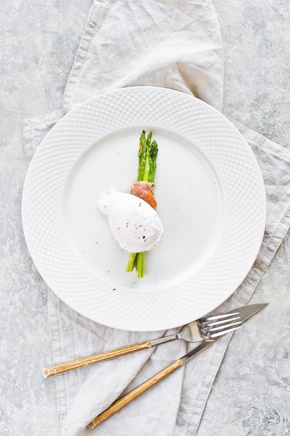 Photo poached eggs on roasted asparagus wrapped in bacon. 