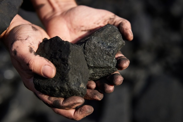 Photo poor middleaged man holding the hands of stone coal for sale to provide food for his family