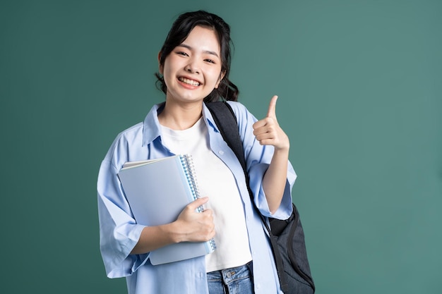 Photo portrait of a beautiful asian student on a green background