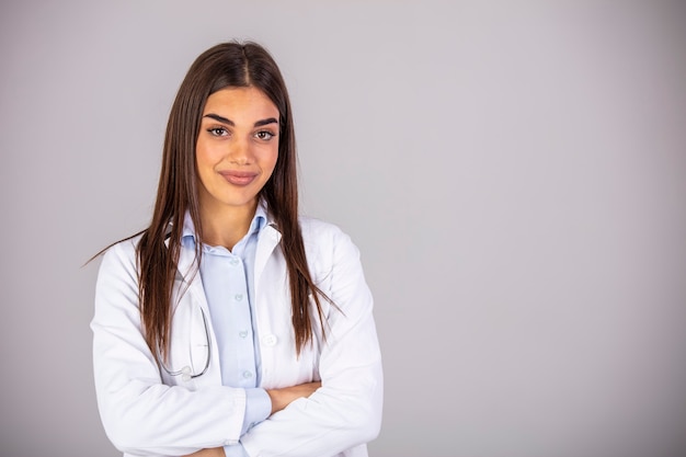 Portrait of confident smiling female doctor. Mid adult medical professional is wearing lab coat and stethoscope. She is standing against gray wall in hospital.