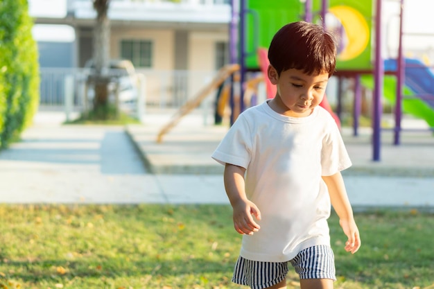 Portrait of cute cheerful baby Asian boy working or running on green grass in at playground