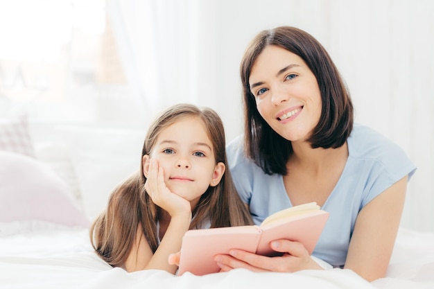 Photo portrait of mother and daughter while standing on bed