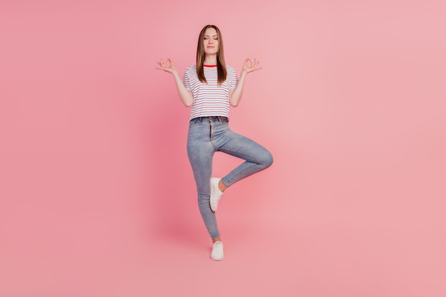 Portrait of peaceful relaxed lady stand one leg meditate enjoy dream on pink background