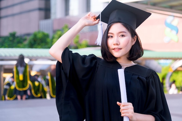 Photo portrait of young woman in graduation gown standing outdoors