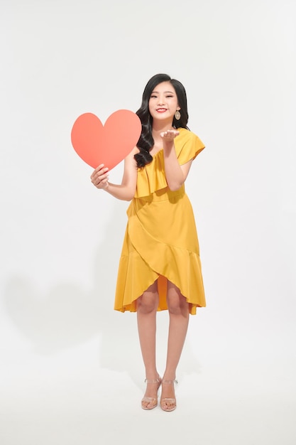 Portrait of young woman with paper heart on color background