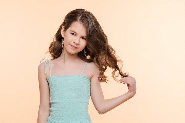 Photo pre-teen girl with beautiful hair in blue dress.