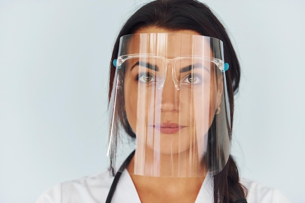 In protective face mask Young female doctor in uniform is indoors