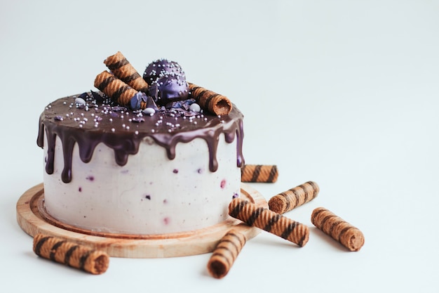 Purple glitter blueberry cake with chocolate glaze on a white surface copy space